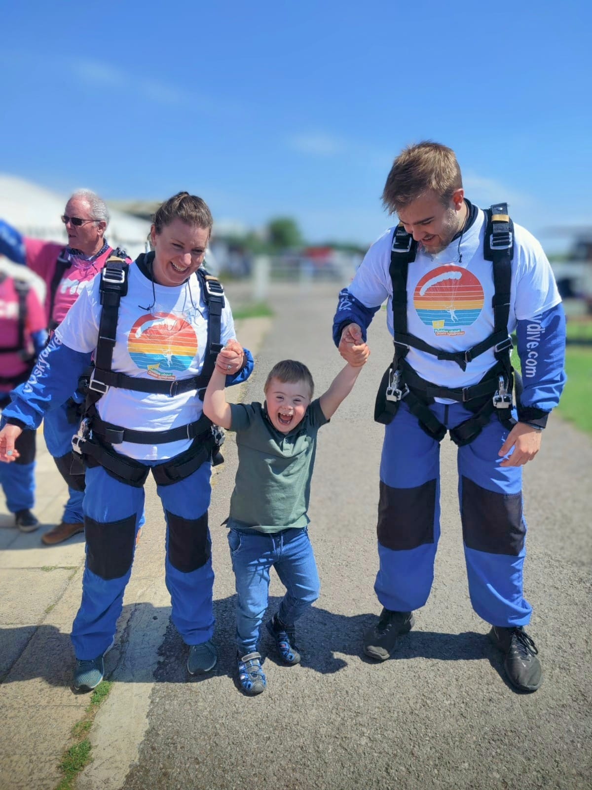 man and woman holding child's hand wearing Skydiving suit
