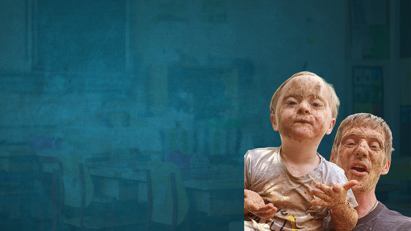 Child being held by dad and smiling for a photo where both their faces are caked in mud!